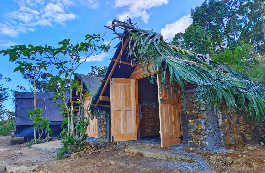 Cabaña pequeña con techo de paja y puerta en Eco Lodge Haputale-Camping Sri lanka, en Haputale