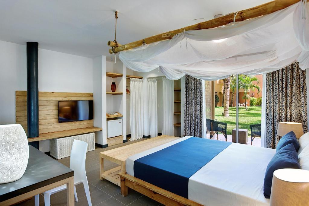 a bedroom with a bed and a table and a tv at Veranda Pointe Aux Biches Hotel & Spa in Trou aux Biches