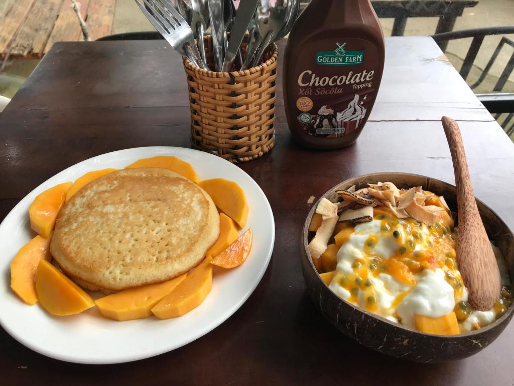 a table with a plate of food and a bowl of eggs and pancakes at Eden House & Coffee Con Dao in Con Dao