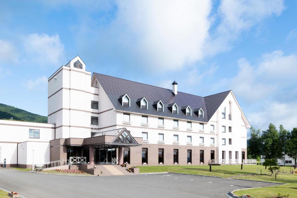 a large white building with a black roof at Hotel Edel Warme in Furano