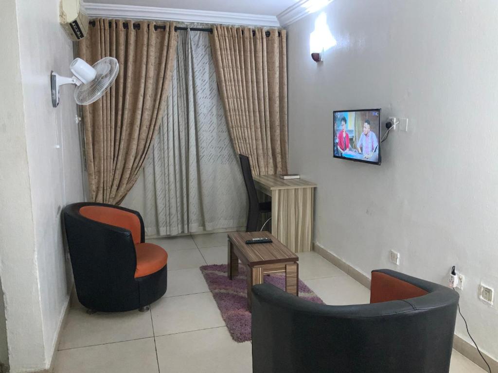 - un salon avec 2 chaises et une télévision murale dans l'établissement DBI GUEST HOUSE, à Lagos