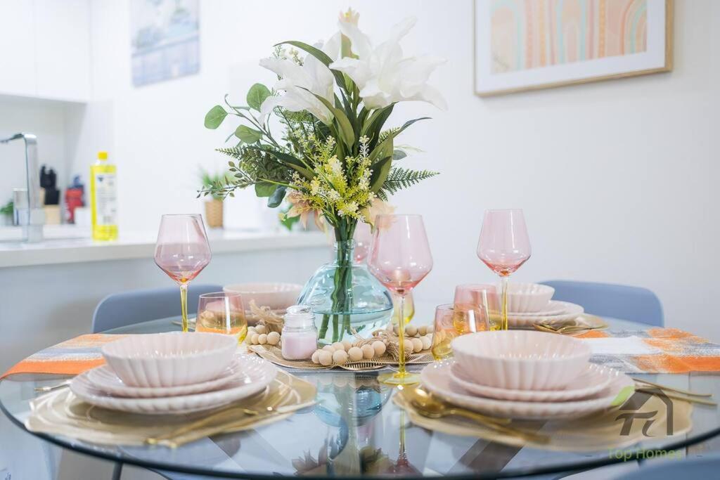 einen Glastisch mit Tellern und Gläsern und eine Vase mit Blumen in der Unterkunft Wonderful Home in Your Heart in Waitara