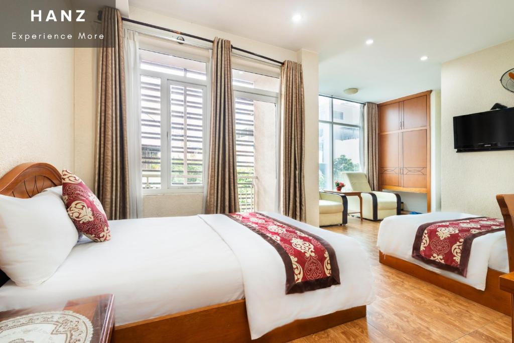 a hotel room with two beds and a window at HANZ Queen Airport Hotel in Ho Chi Minh City