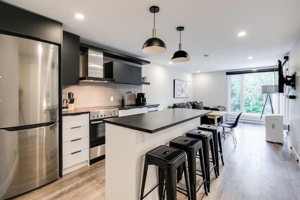 a kitchen with black and white appliances and stools at Le PanoramiK by Gestion ELITE in Mont-Tremblant