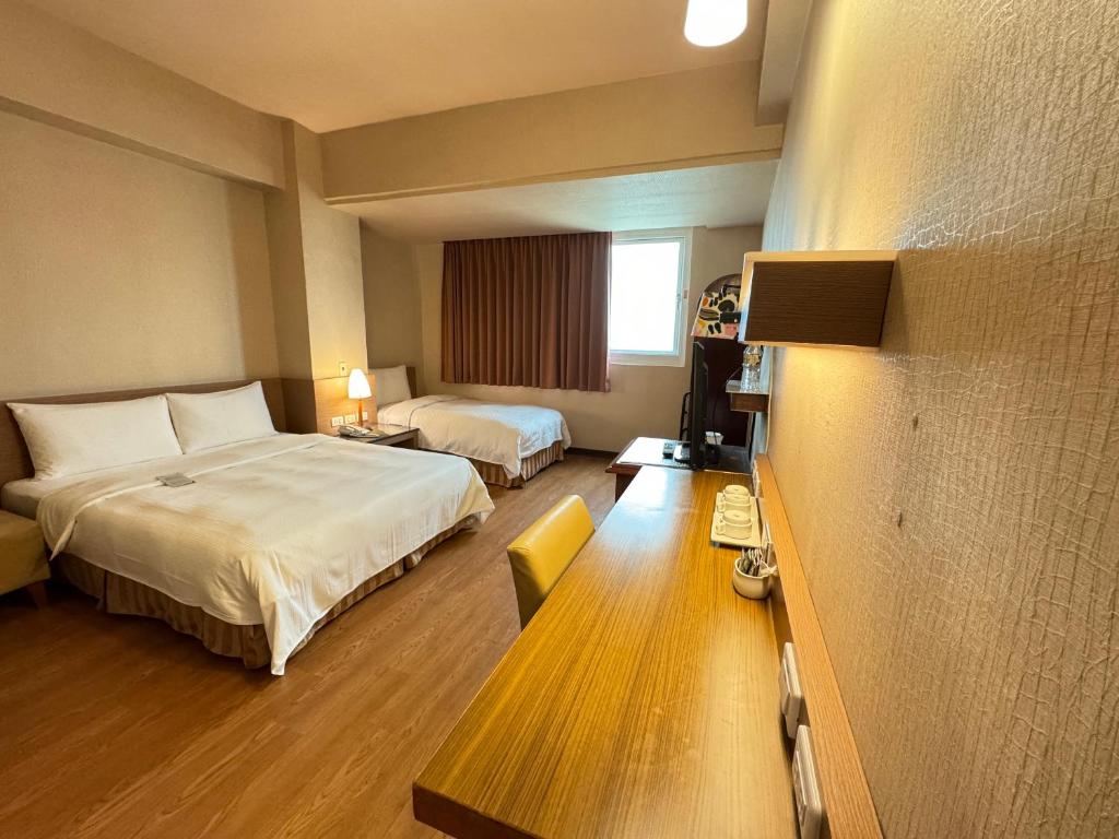 a hotel room with two beds and a window at Kindness Hotel Wu-Jia in Kaohsiung