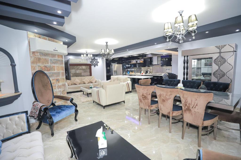 ein Wohnzimmer mit einem Tisch und Stühlen sowie eine Küche in der Unterkunft Heliopolis Heights, 3-Bedroom Grandeur, Jacuzzi, 5 AC & 4 TVs in Kairo