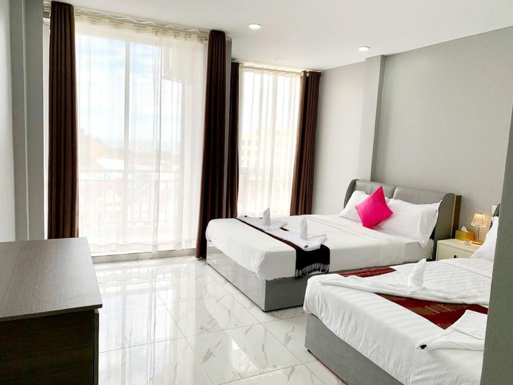 a hotel room with two beds and a large window at Sok Eng Hotel ( សណ្ឋាគារ សុខ អេង ) in Sihanoukville