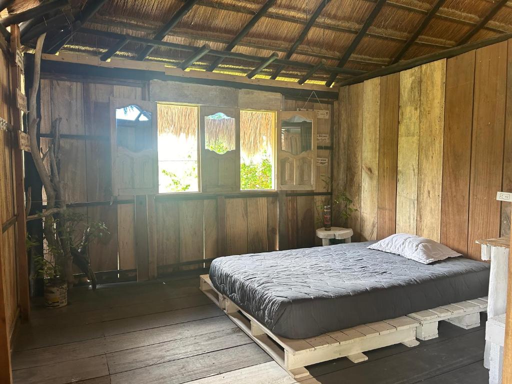 Playa Punta ArenaにあるPunta Arena EcoHostal & EcoFit - Your Eco-Friendly Oasisの木製の部屋にベッド1台が備わるベッドルーム1室があります。