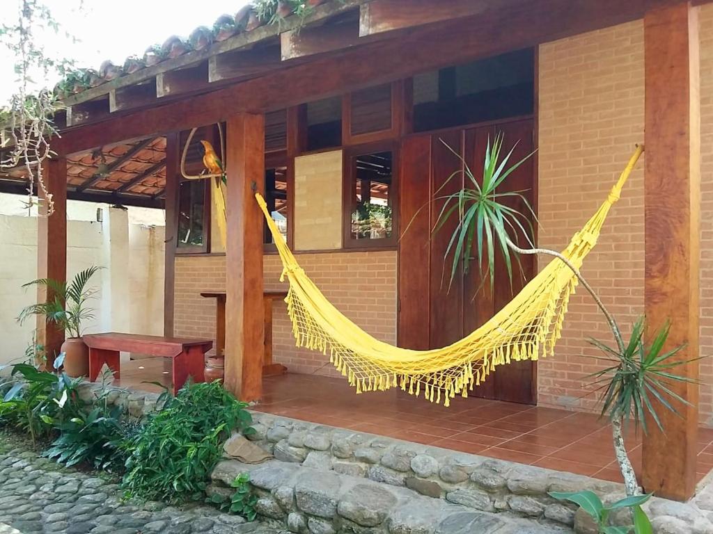una hamaca amarilla colgada de un lado de una casa en CASA em UBATUBA, en Ubatuba