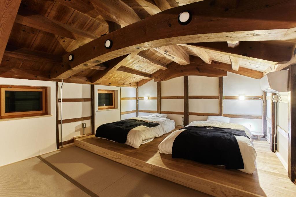 2 łóżka w pokoju z drewnianym sufitem w obiekcie 城崎温泉一棟貸しの宿　ゆっ蔵 w mieście Toyooka