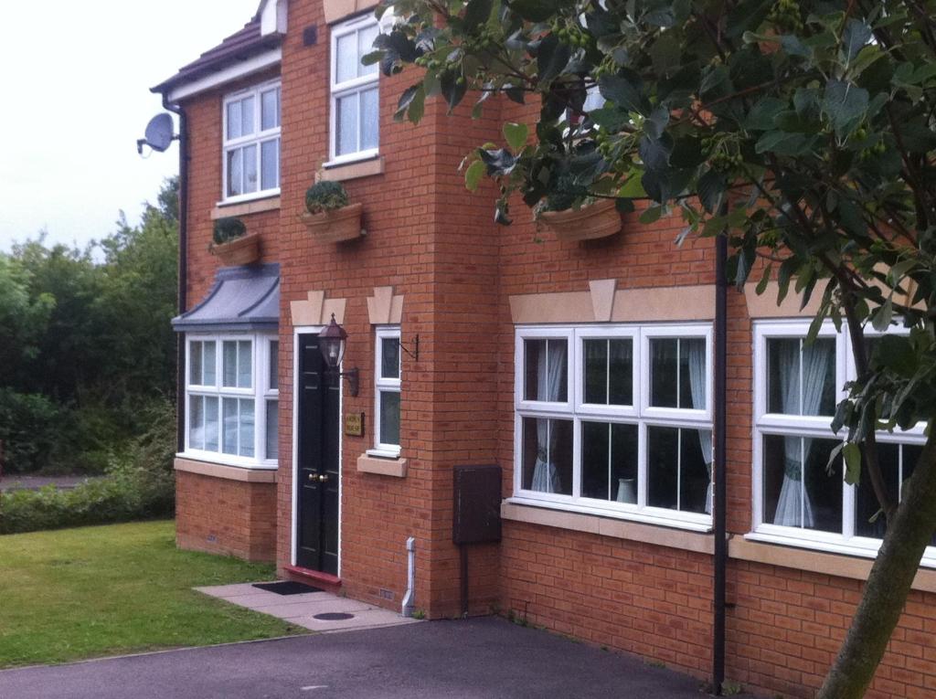 uma casa de tijolos com uma porta preta e janelas em Arden House NEC Birmingham em Bickenhill