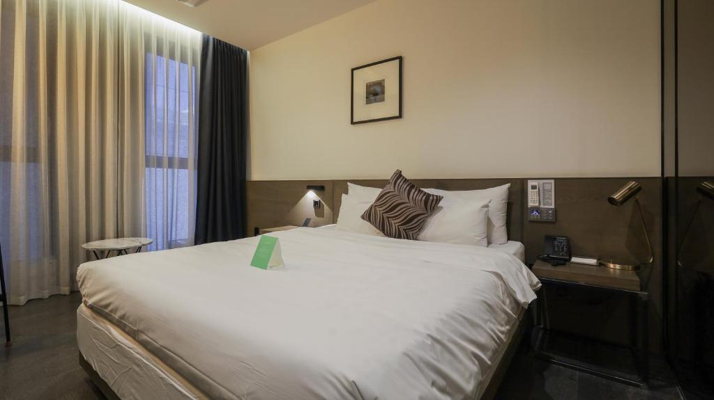 Kynd Hotel في سيونغنام: غرفة فندقية بسرير كبير ونافذة