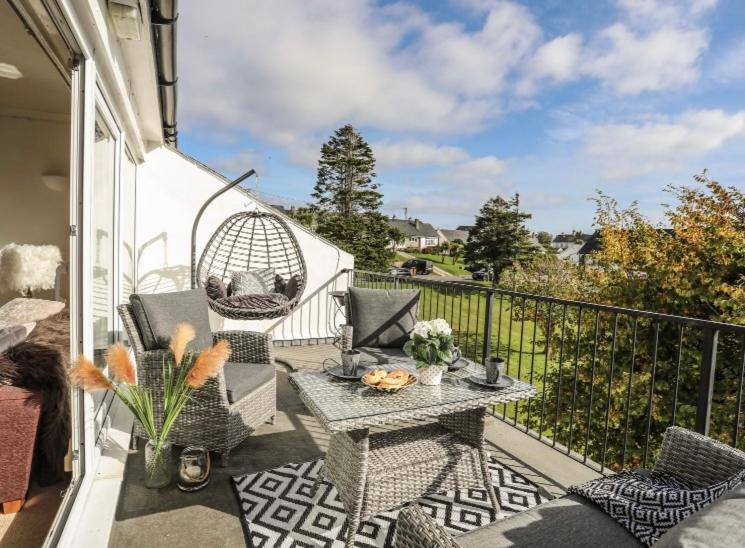 a patio with a table and chairs on a balcony at 27 Cae Du in Abersoch