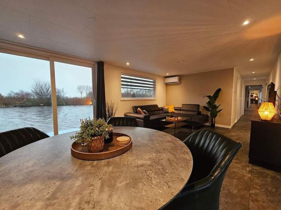 a living room with a large wooden table and chairs at Luxe woonboot in de natuur evt met console bootje! in Leeuwarden