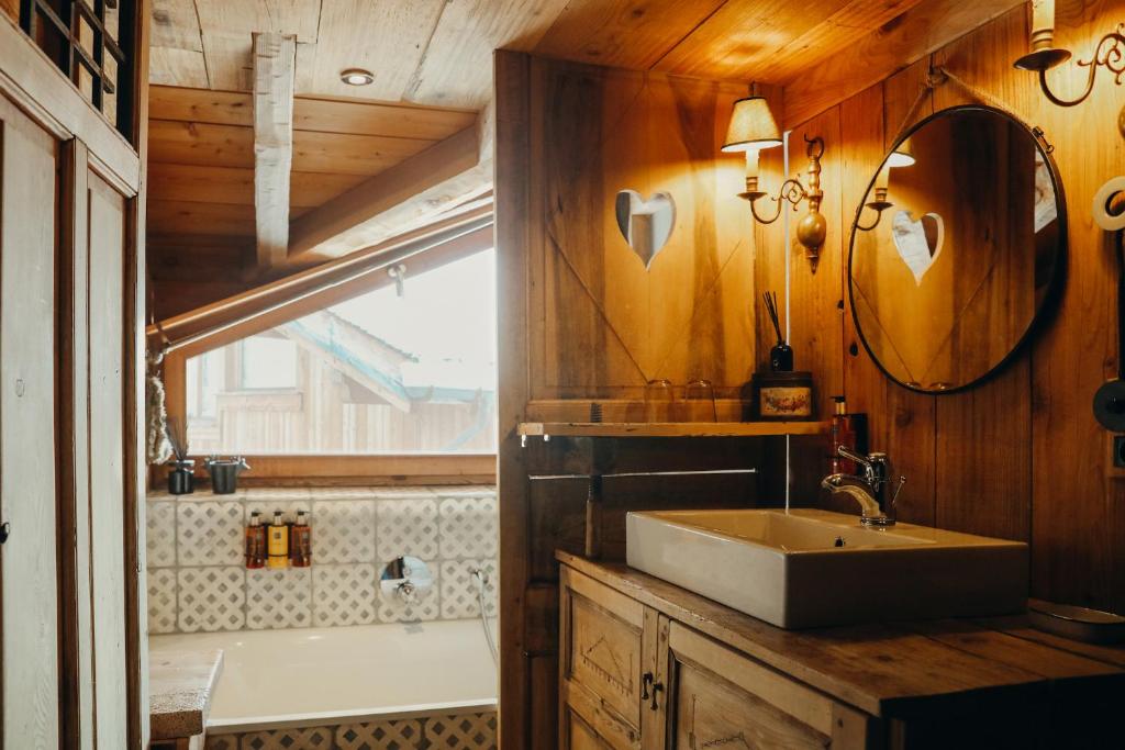 La salle de bains est pourvue d'un lavabo, d'une baignoire et d'un miroir. dans l'établissement Joubarbe Rose By Lodji, à Saint-Martin-de-Belleville