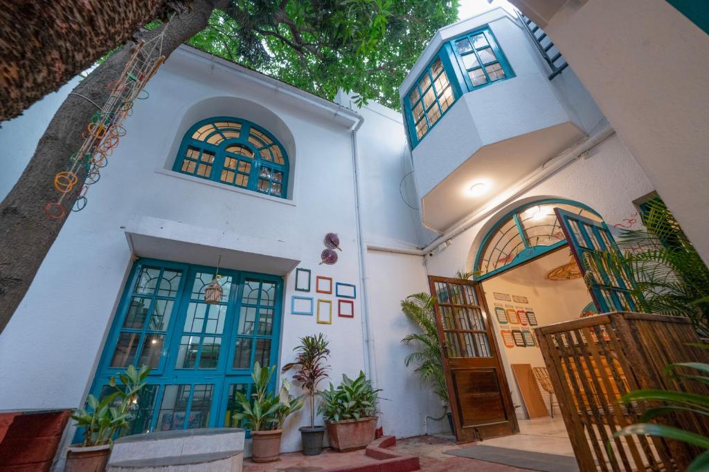 a white house with blue doors and potted plants at House of Stories - Indiranagar in Bangalore