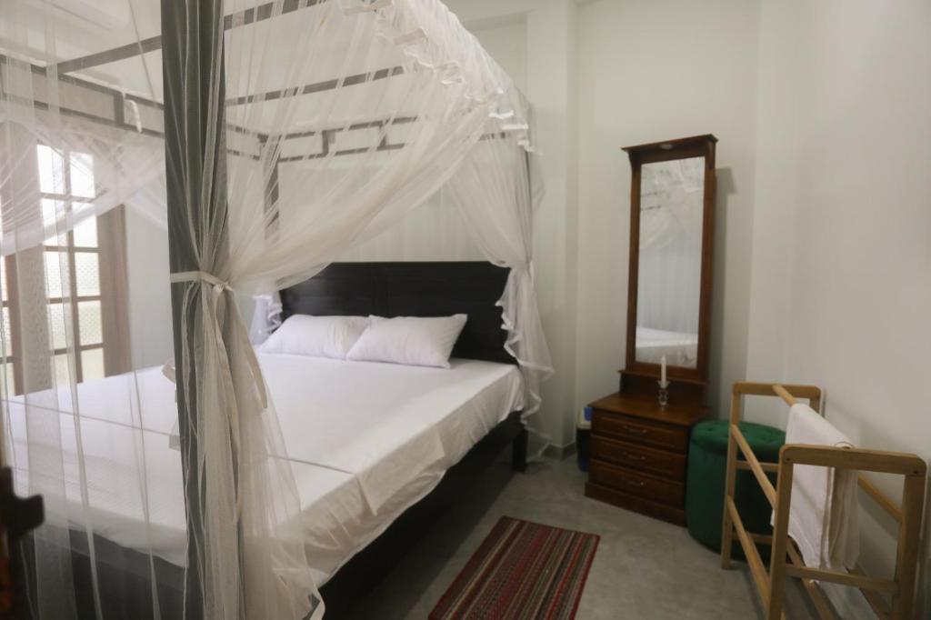 1 dormitorio con cama con dosel y espejo en cric villa en Galle