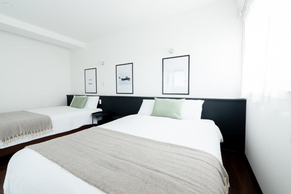 浦添的住宿－BREAKY HOTEL west coast，白色墙壁客房的两张床