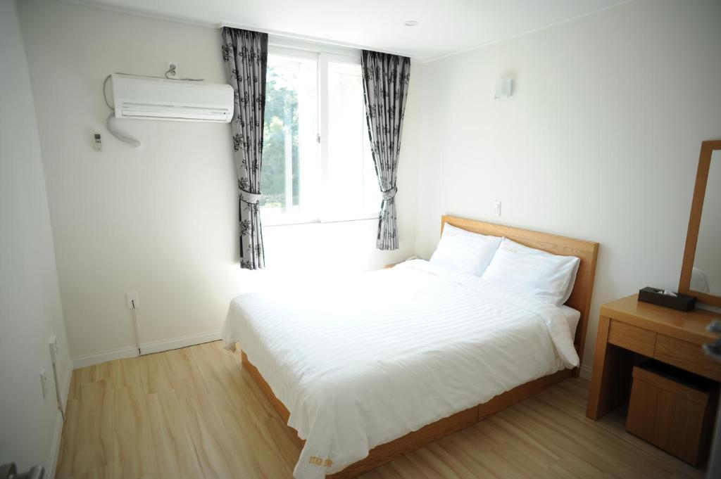 1 dormitorio con 1 cama con sábanas blancas y ventana en Star House en Jeju