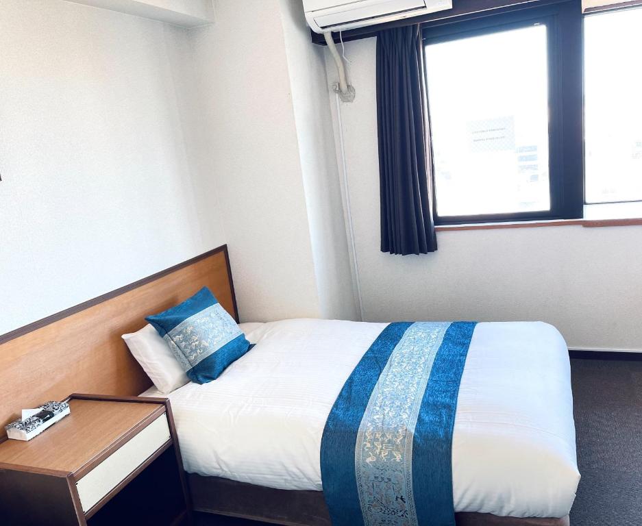 1 dormitorio con 1 cama con manta azul y blanca en Ogaki Hiyori Hotel - Vacation STAY 90796v en Ogaki