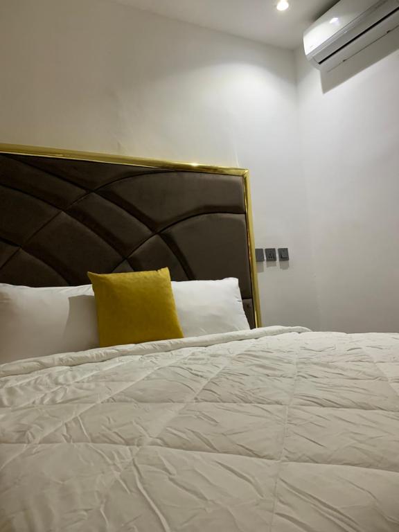 a large white bed with a yellow pillow on it at Iyoba Apartment in Abuja