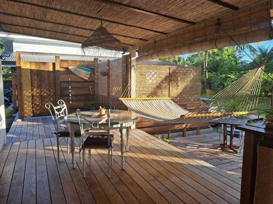 a patio with a hammock and a table and chairs at Breeze Ocean Bungalow Moorea in Moorea