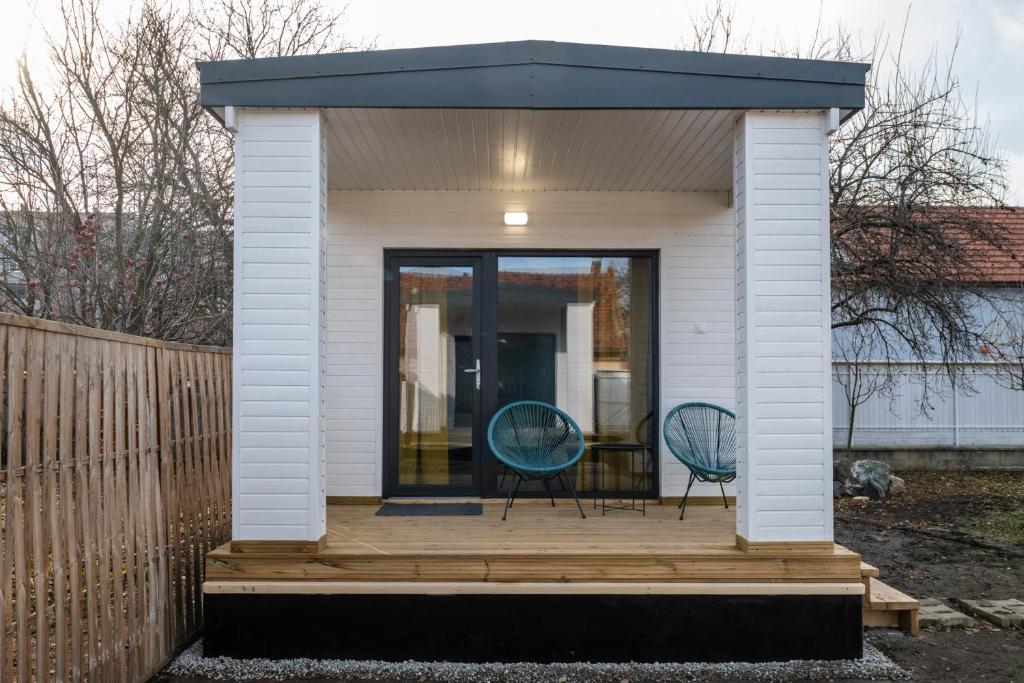 a tiny house with two chairs on a deck at Tiny Village in Târgu Secuiesc