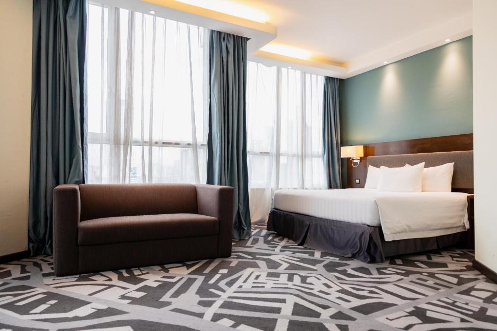 Habitación de hotel con cama y silla en WP Hotel en Kuala Lumpur