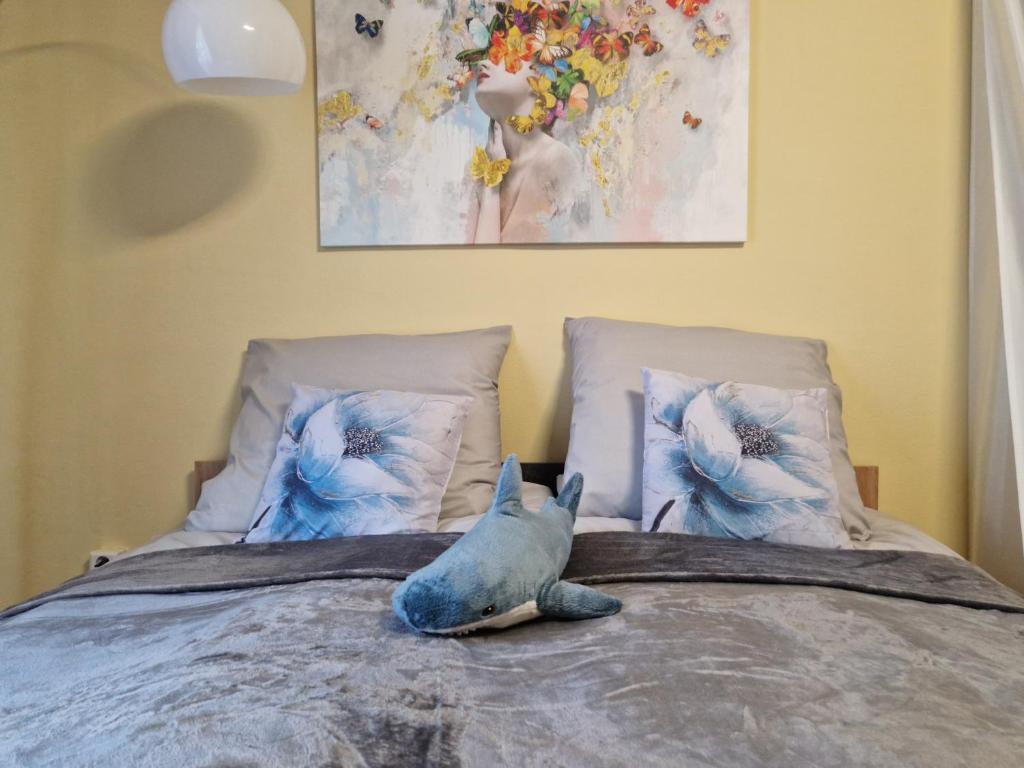 a stuffed dolphin sitting on a bed with pillows at Veludo Apartments Centrum free parking in Banská Bystrica