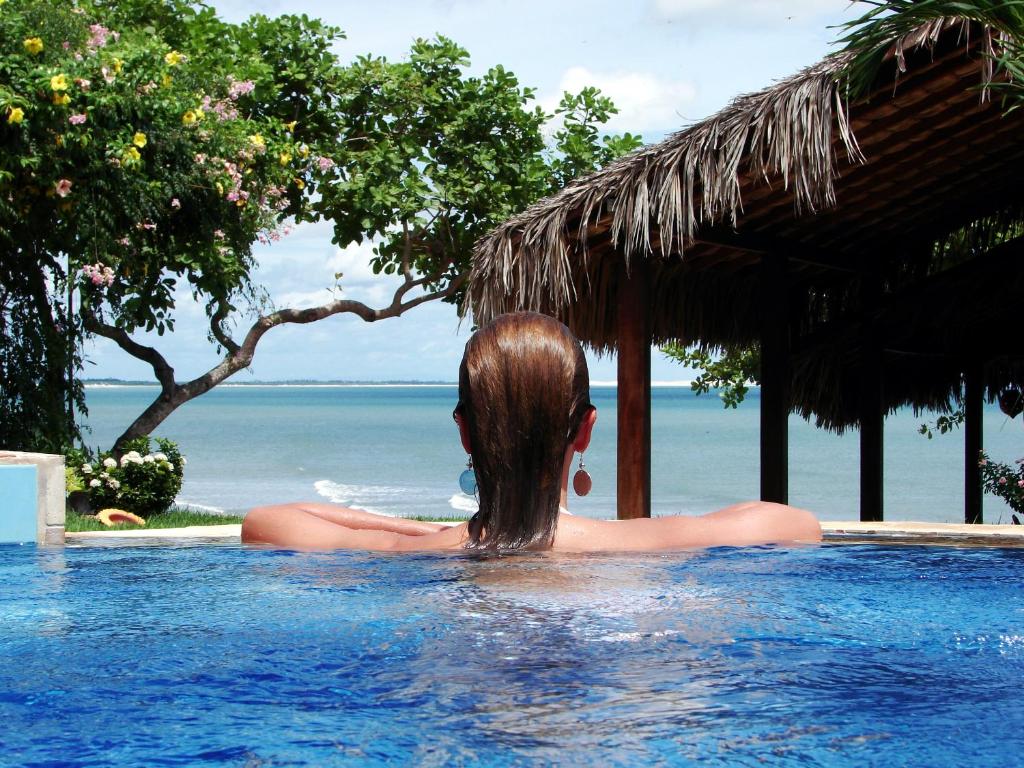 Una mujer en una piscina con vistas al océano en Pousada Jeribá, en Jericoacoara