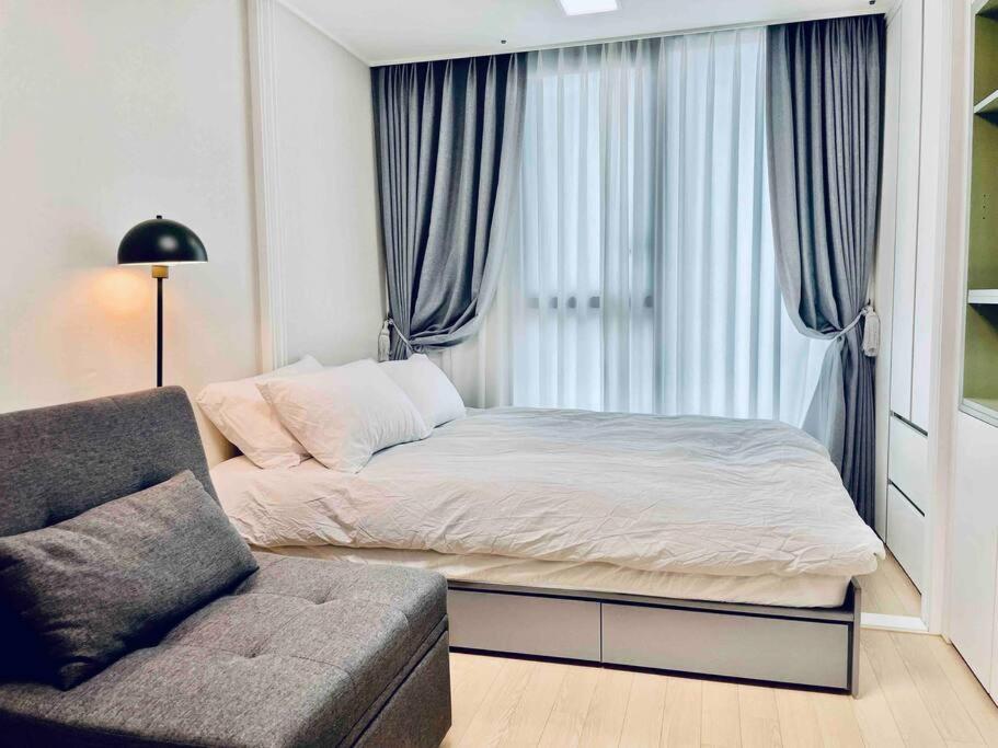 1 dormitorio con cama, sofá y ventana en NEST Myeongdong Residence high-rise floor #Namsan #Hanok village #Gyeongbok palace #Euljiro en Seúl