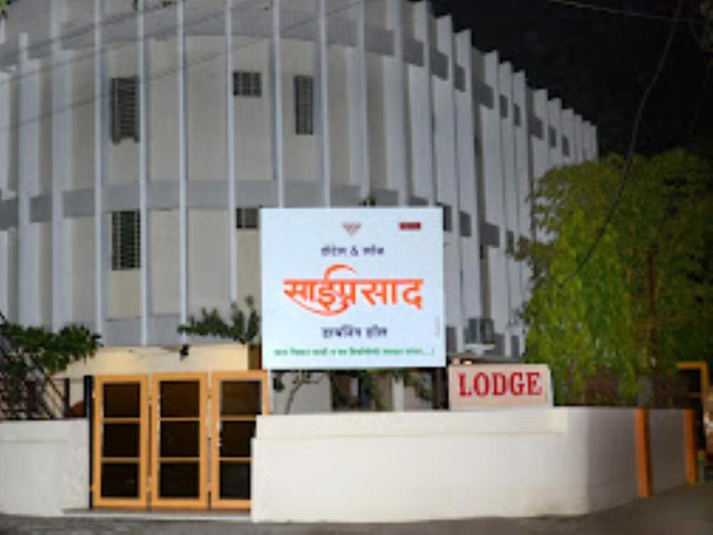 een wit gebouw met een bord ervoor bij HOTEL SAIPRASAD LODGE Solapur in Solapur