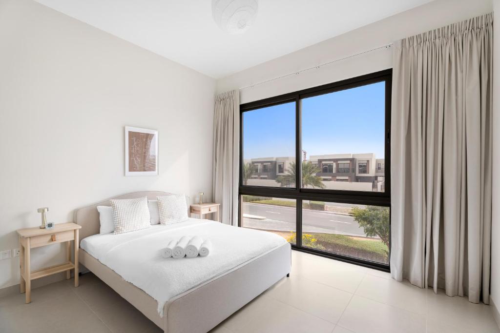 a bedroom with a white bed and a large window at Lovely 3BR Villa in Dubai EXPO in Dubai