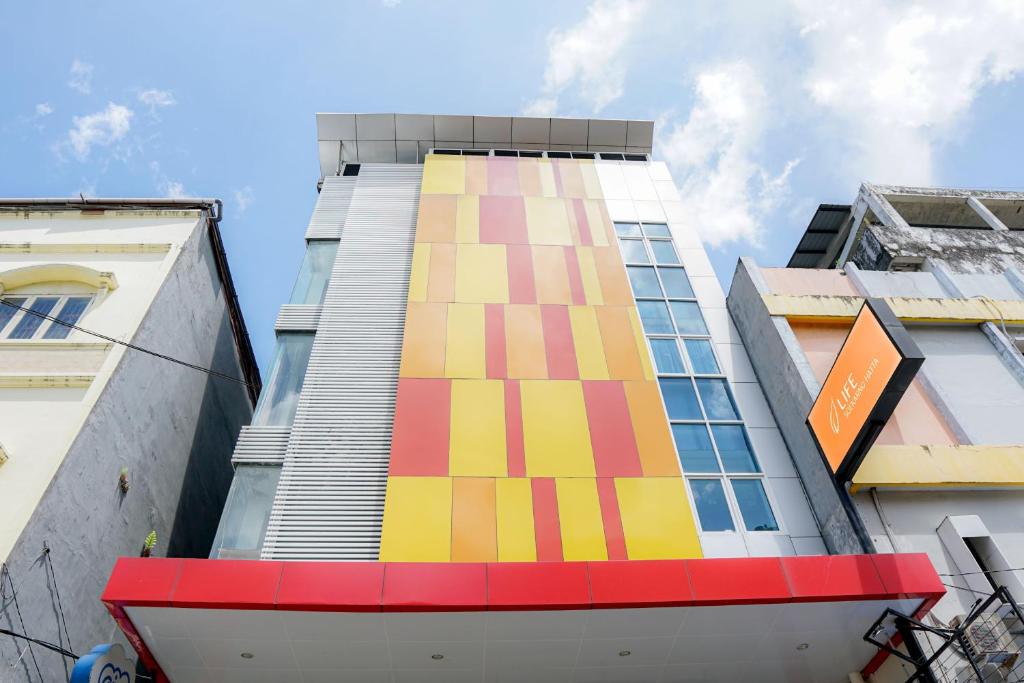 ein hohes Gebäude mit farbenfroher Farbe auf der Seite in der Unterkunft Life Hotel Soekarno Hatta Makassar in Makassar