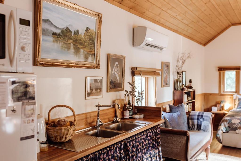 a kitchen with a sink and a living room at Hideaway Farmlet Romantic Cottage with Miniature Goats in Penguin
