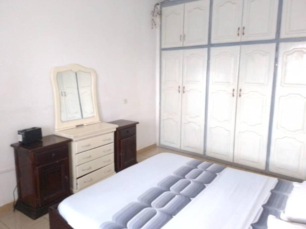a bedroom with a bed and a dresser and a mirror at Appart meublé le Dakota in Yaoundé