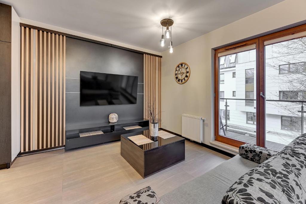 salon z kanapą i telewizorem na ścianie w obiekcie Aquarius by Grand Apartments w mieście Sopot