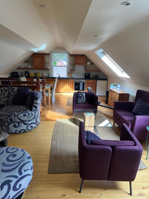 a living room with purple couches and a kitchen at Self Contained Coach House in Leafy South Belfast the location is not accurate in Belfast