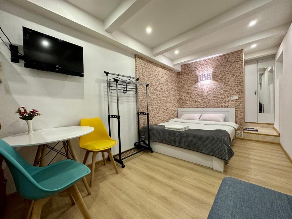 um quarto com uma cama, uma mesa e cadeiras em George's Studio Apartment on Liberty Square em Tbilisi