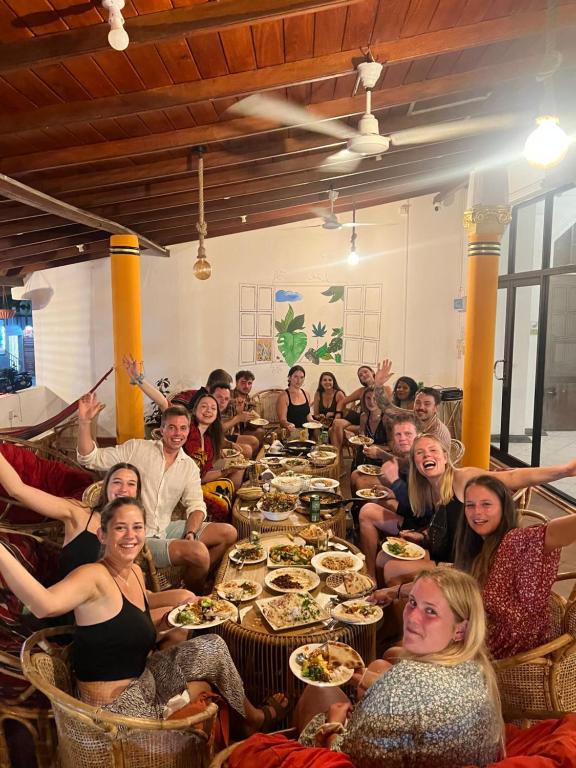 un grupo de personas sentadas en una mesa larga en Hummus Hostel & Restaurant en Hikkaduwa