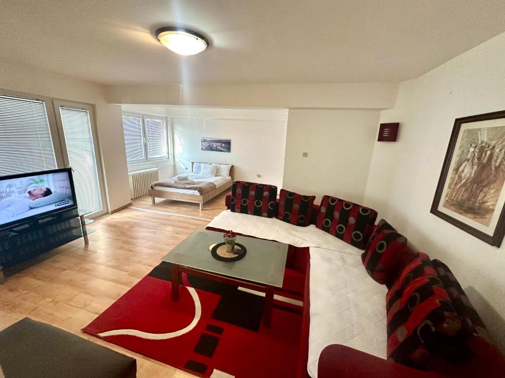 ein Wohnzimmer mit einem roten Sofa und einem TV in der Unterkunft Aleks 4 in Skopje