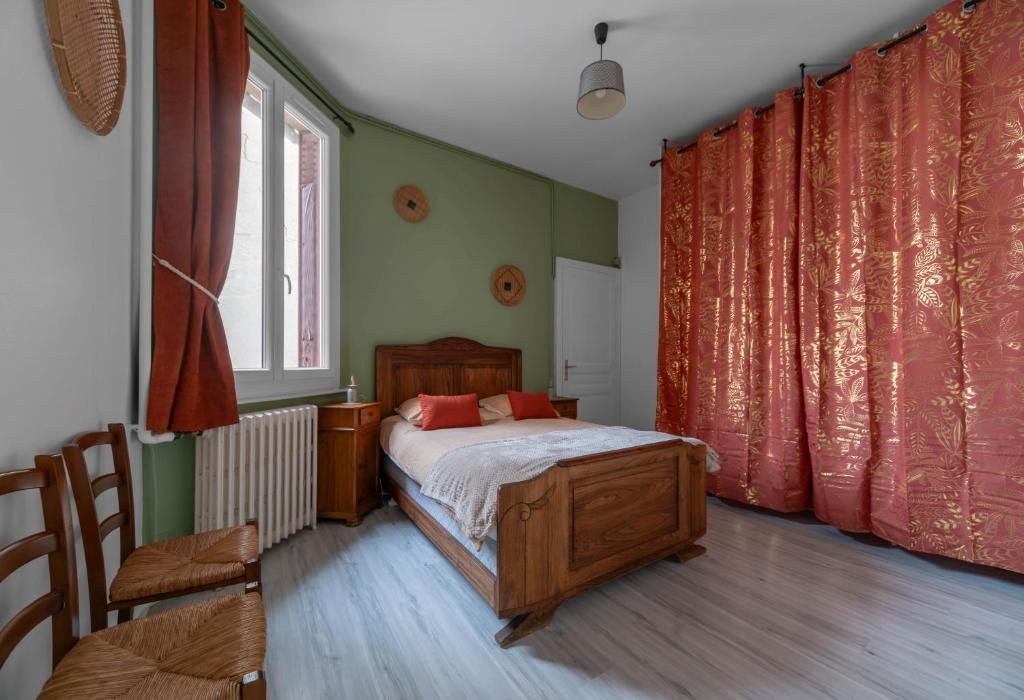 Schlafzimmer mit einem Bett mit roten Vorhängen und einem Tisch in der Unterkunft Le Louis B - Appartement calme et lumineux proche Thermes in Vichy