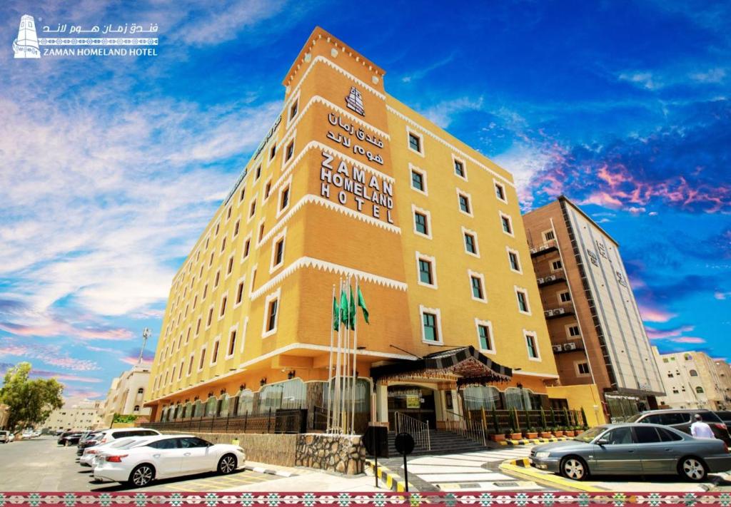 فندق زمان هوم لاند Zaman Homeland Hotel في الطائف: مبنى أصفر طويل وبه سيارات متوقفة في موقف للسيارات