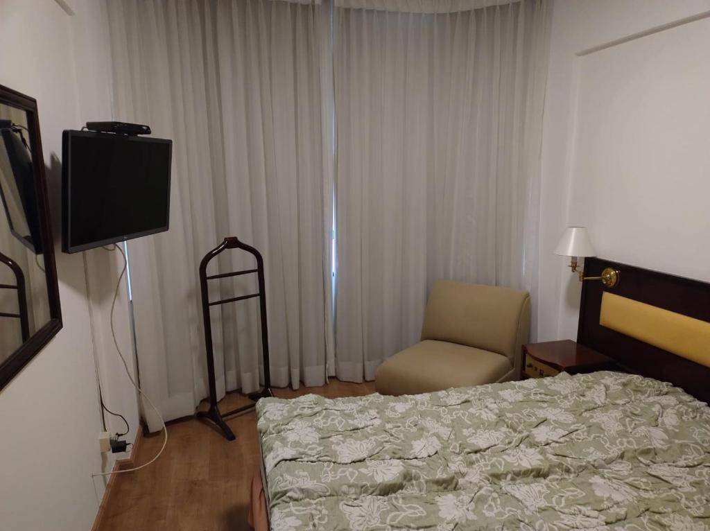 a bedroom with a bed and a chair and a television at Flat completo - Campinas Centro in Campinas