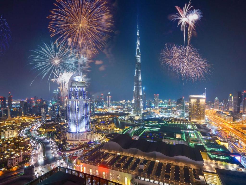 uma vista para uma cidade com fogos de artifício no céu em 2 BR Superior High Floor Apartment in Paramount Midtown, Burj Khalifa View em Dubai