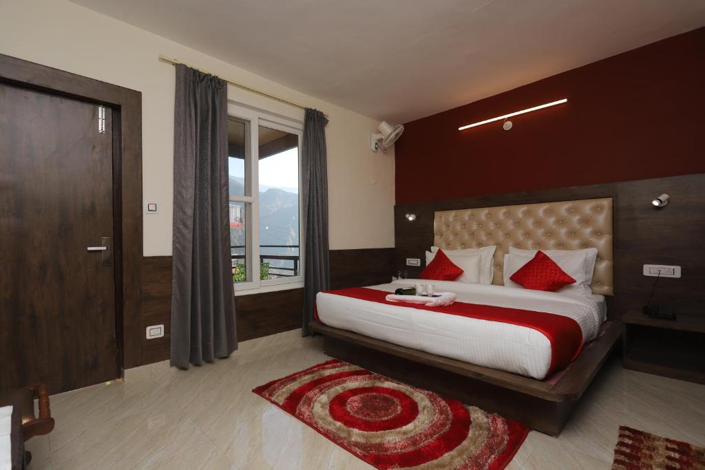 a bedroom with a bed with red pillows and a window at The Nest with open rooftop cafe Mecleodganj in Dharamshala