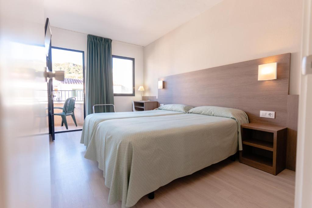 a bedroom with a large bed and a balcony at Apartamentos Loar in Ferreries