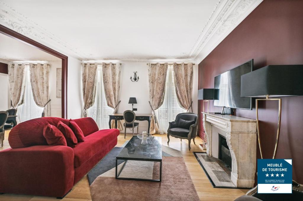 uma sala de estar com um sofá vermelho e uma lareira em Séjours Parisiens / Suite Le Royal / 4* em Paris