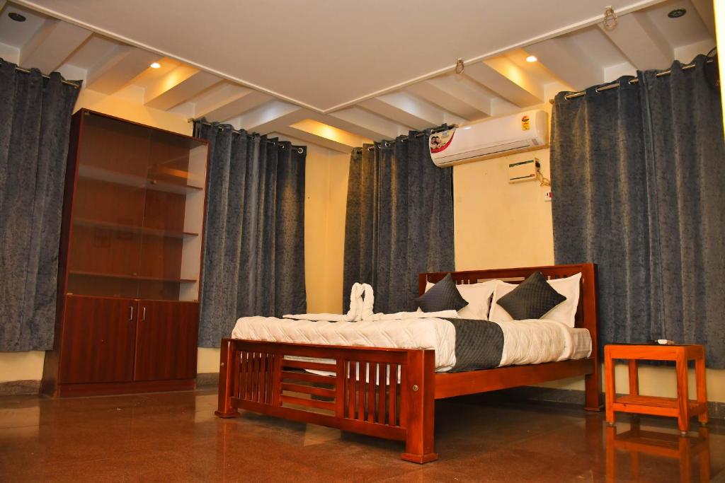 Revive Inn Pondy - Rooms & Villa في بونديتْشيري: غرفة نوم بسرير خشبي مع ستائر