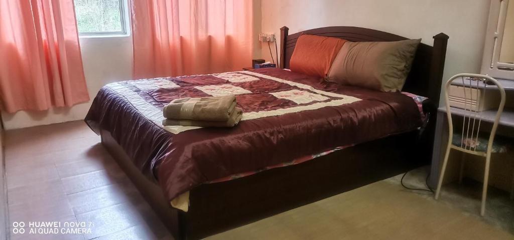 ein Schlafzimmer mit einem Bett mit einer Decke darauf in der Unterkunft EBH2 Guesthouse in Kampong Alor Gajah